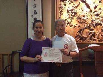 Maître Yan remet le diplome de Qi Gong de professeur de Qi Gong forme yi Jing Jin en août 2015.